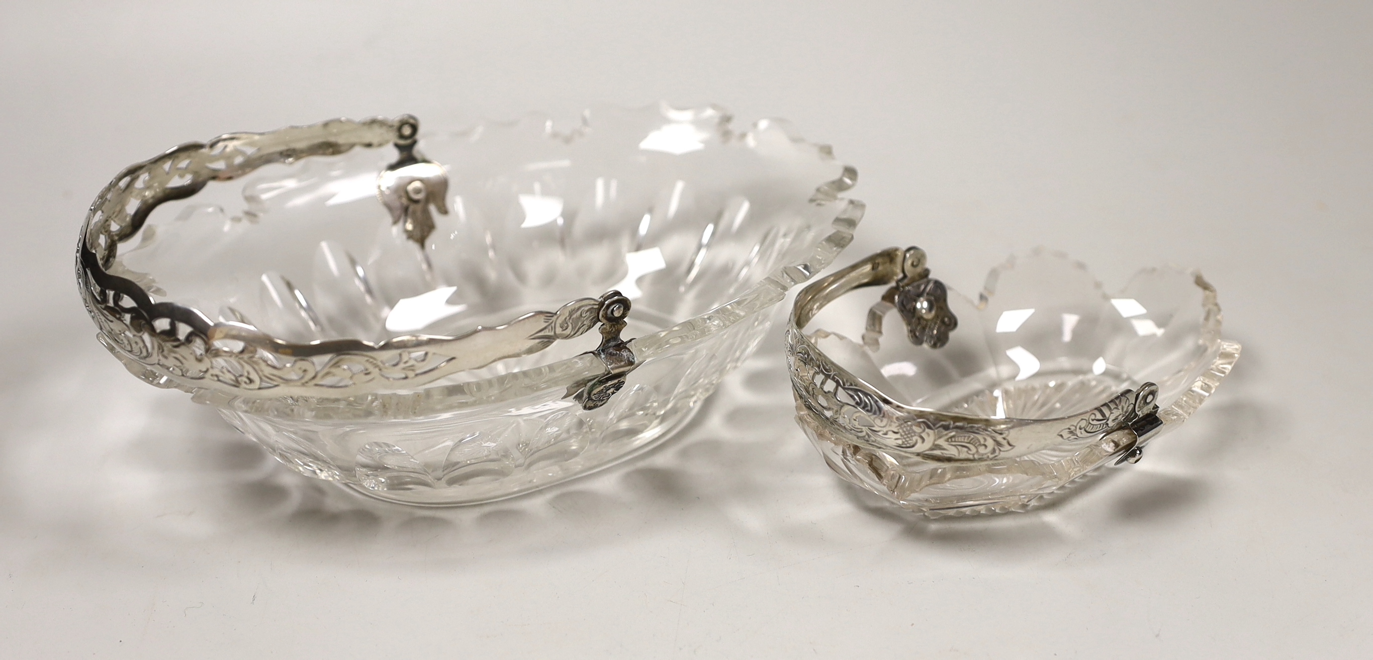 A late 19th century Dutch white metal mounted cut glass sweetmeat basket, length 21.4cm and a similar smaller basket.